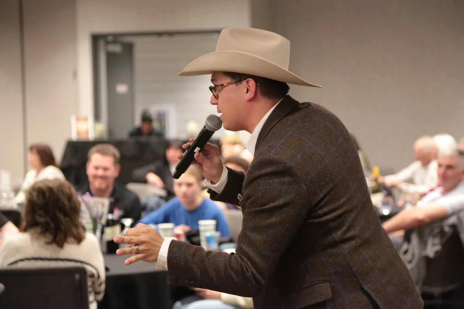 Tanner Beymer on the microphone mid-call, working between tables of bidders at a live benefit auction